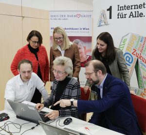 Gruppenbild von Mitarbeitern, die auf einen Laptop schauen, Stichwort Internet für alle. (c) BKA/ Regina Aigner