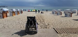 Ein Rollstuhl vor einem Sandstrand, Stichwort barrierefrei reisen. (c) Pixabay.com