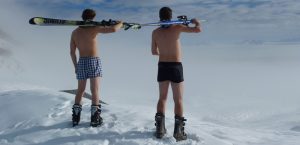 Zwei Männer in Unterhose mit Schischuhen und Ski auf den Schultern, Stichwort sportlich gesund unterwegs. (c) Pixabay.com