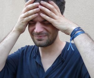 Ein Mann greift sich vor Schmerzen mit den Händen an die Stirn, Stichwort Stirnhöhlen. (c) Pixabay.com