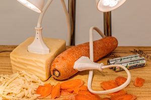 Leuchtende Lampen, die in einem Stück Käse bzw. in einer Karotte eingesteckt sind, Stichwort Nachhaltigkeit. (c) Pixabay.com