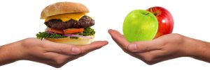 Eine Hand mit einem Burger, eine mit zwei Äpfel, Stichwort braune Fettzellen. (c) Pixabay.com