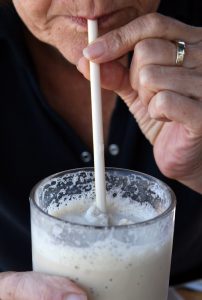 Eine Frau, die mit einem Strohhalm aus einem Glas Milchshake trinkt, Stichwort wenn Essen krank macht. (c) Pixabay.com