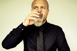 Ein Mann beim Trinken aus einem Wasserglas, Stichwort Mundtrockenheit. (c) Pixabay.com