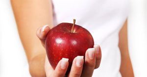 Die Hand einer Frau, die einen roten Apfel hält, Stichwort Obst. (c) Pixabay.com