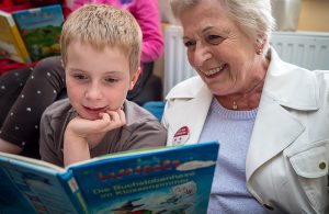 Eine Seniorin, die mit einem Kind ein Buch liest, Stichwort freiwilliges Engagement. (c) ÖRK/ Robert Holzer