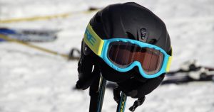 Ein Skihelm mit Brille hängt auf zwei Skistöcken.