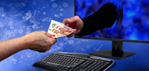 Die Hand einer Frau, die einer aus einem Monitor ragenden Hand eines Mannes Geldscheine gibt. (c) Pixabay.com