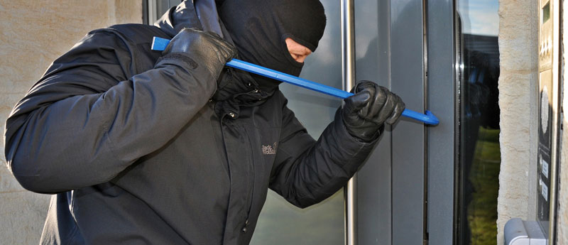 Ein Einbrecher mit Gesichtsmaske, der mit einem Brecheisen eine Tür aufbricht, Stichwort Sicherheit in den eigenen vier Wänden. (c) Pixabay.com