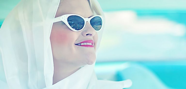 Profil einer lächelnden Golden Agerin mit weißem Kopftuch und weißer Sonnenbrille. (c) Pixabay.com