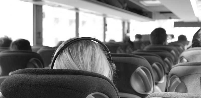 Eine Person mit Kopfhörern in einem Reisebus. (c) Pixabay.com