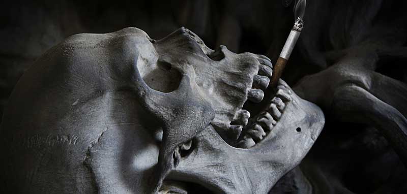 Ein liegender Totenkopf mit einer Zigarette zwischen den Zähnen. (c) Pixabay.com