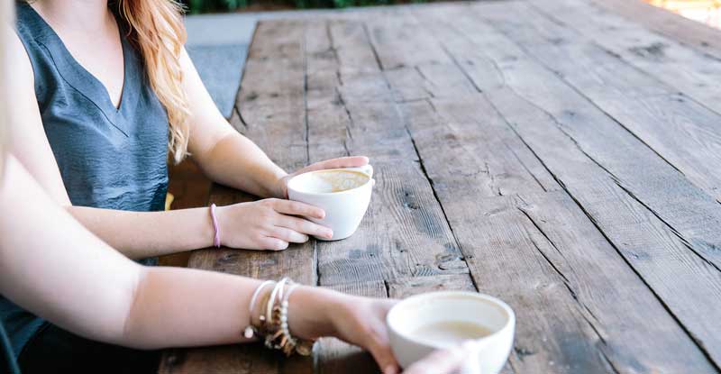 Bildausschnitt: die Hände zweier Frauen, die an einem Tisch sitzen und Kaffee trinken. (c) Pixabay.com