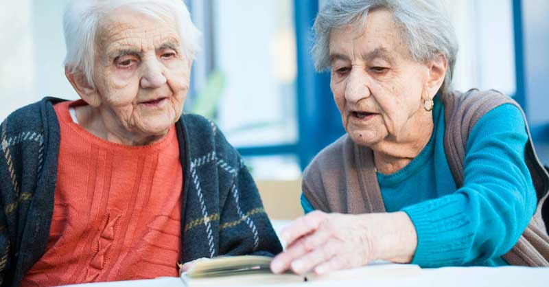 Zwei alte Frauen, die sich ein Buch anschauen. Eine von ihnen ist an Demenz erkrankt. (c) Nadja Meister/ Diakonie Österreich