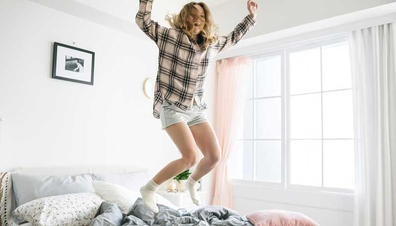 Eine Frau, die vor Freude im Bett in die Höhe springt. (c) Pixabay.com