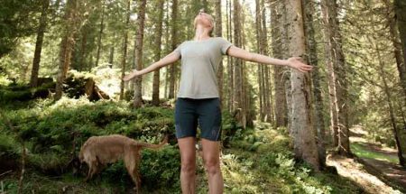 Eine Frau mit weit zur Seite gestreckten Armen beim Waldbaden. (c) Manuel Marktl