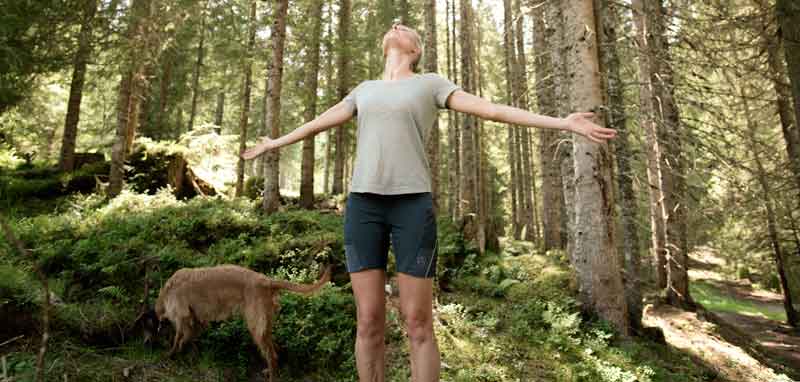 Eine Frau mit weit zur Seite gestreckten Armen beim Waldbaden. (c) Manuel Marktl