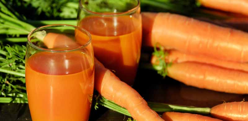Vitamin-Überdosis – gibt es sowas und wenn ja, ist das schädlich? 2 Gläser mit Karottensaft zwischen liegenden Karotten. (c) Pixabay.com