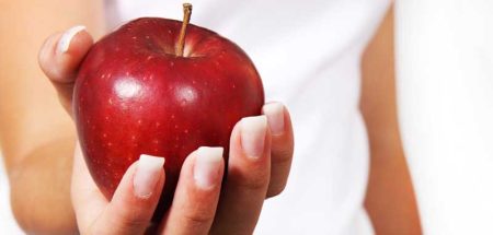 Eine Frauenhand, die einen roten Apfel hält. (c) Pixabay.com