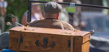 Ein alter Mann in einem Oldtimer Cabrio, bei dem hinten ein Koffer fixiert ist. (c) Pixabay.com