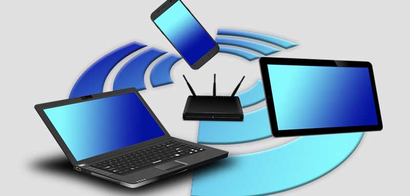 Digital Detox: Laptop, Handy und Tablet fliegen um eine W-Lan Station herum. (c) Pixabay.com