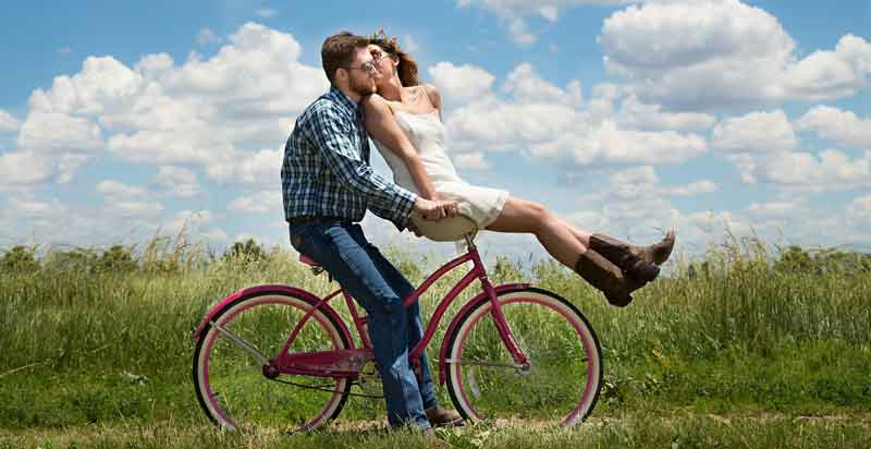 Eine Frau sitzt auf der Lenkgabel eines Fahrrades und küsst den Mann, der auf dem Fahrrad sitzt. (c) Pixabay.com