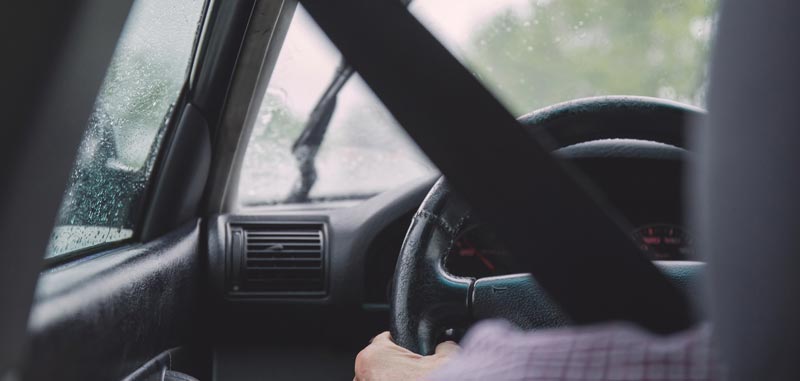 Ausschnitt eines Autofahrers von hinten; man sieht das Lenkrad, und dass es regnet. (c) Pixabay.com