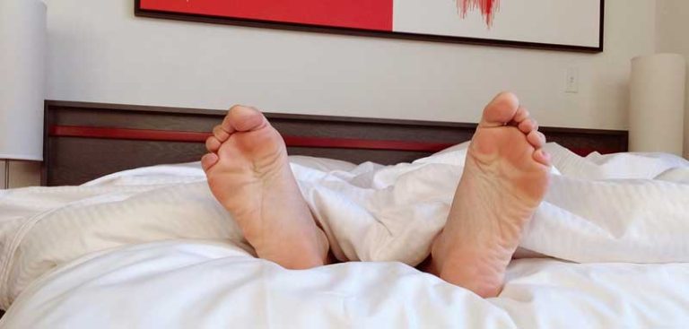 Die Füße eines Mann in einem Hotelbett. (c) Pixabay.com