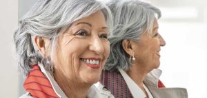 Individualisiertes Hören – Hör-Implantate mit dem Handy einstellen Eine ältere Frau mit Hörimplantat vor einem Spiegel. (c) MED-EL.