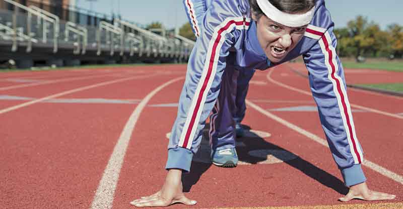 Ein Frau mit verbissenem Gesichtsausdruck beim Start eines Laufes auf einer Laufbahn. (c) Pixabay.com
