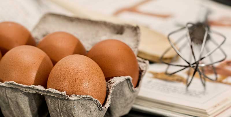 Eier und ein Schneebesen auf einem Tisch, auf dem gebacken wird. (c) Pixabay.com