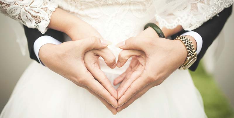 Die Hände eines Brautpaares zu einem Herz geformt vor dem Bauch der Braut. (c) Pixabay.com