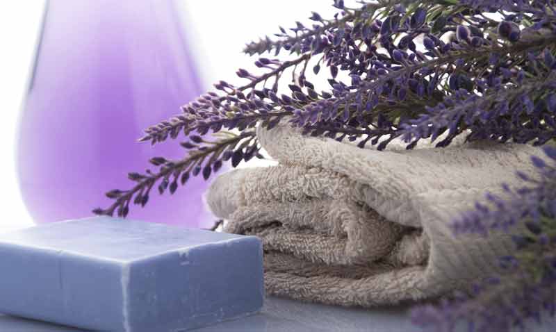 Für die Badewanne: Lavendelseife, ein Handtuch und im Hintergrund Lavendelöl. (c) Pixabay.com