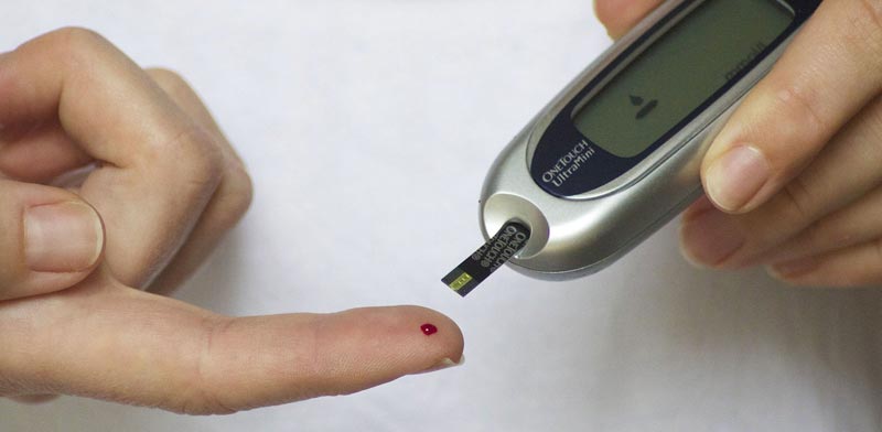 Diabetes – ein kleiner Bluttropfen auf einem Zeigefinger und ein Blutzuckermessgerät. (c) Pixabay.com