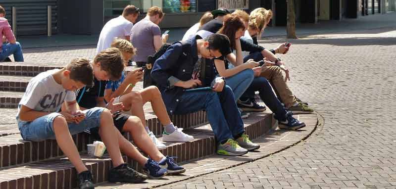 Jugendliche der "Generation Greta", die auf einer Stufe in einer Fußgängerzone sitzen und alle auf ihre Handys schauen. (c) Pixabay.com