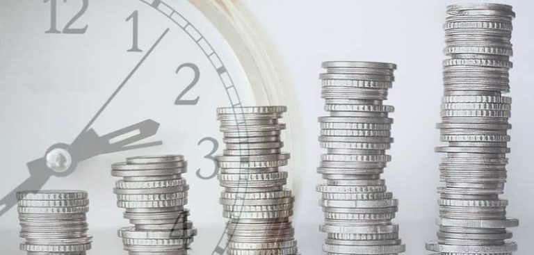 Fünf immer größer werdende Stapel von Münzen, im Hintergrund eine Uhr. (c) Pixabay.com