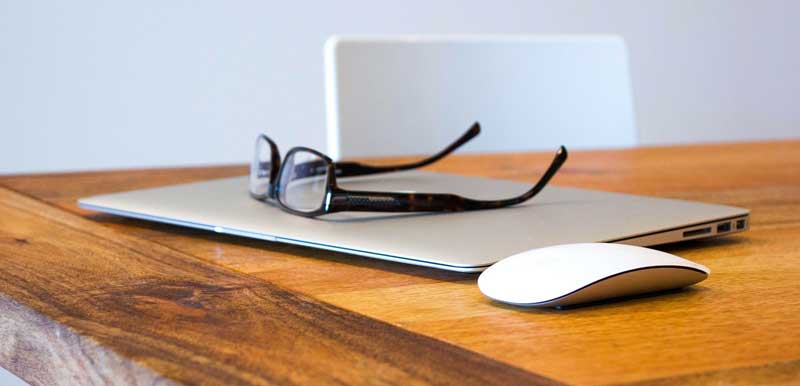 Eine Brille auf einem Laptop, daneben eine kabellose Computermaus auf einem Tisch, Stichwort Augengesundheit. (c) Pixabay.com