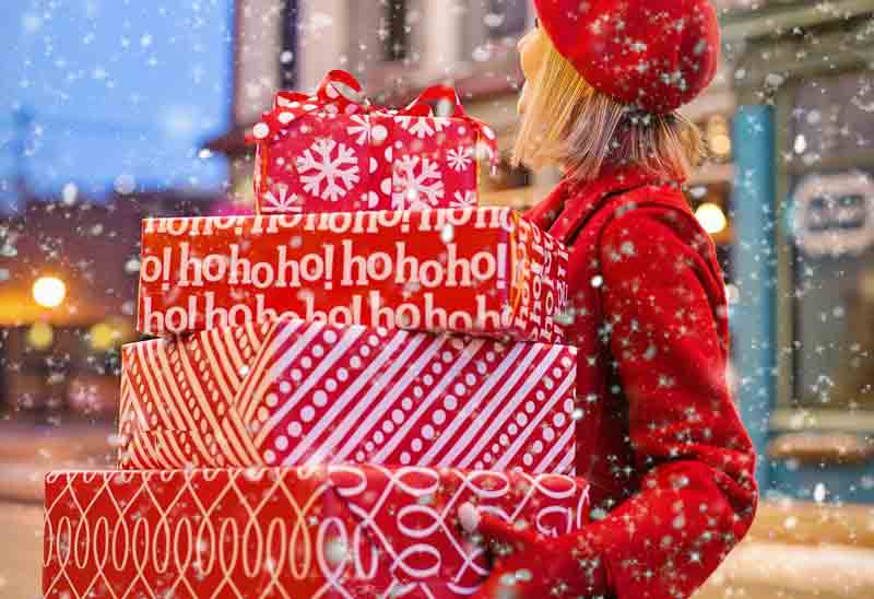 Eine Frau trägt mehrere Weihnachtspakete, Stichwort Geschenke. (c) Pixabay.com