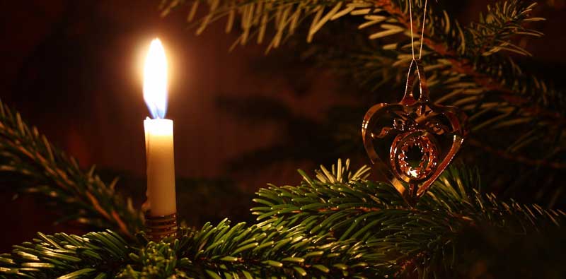 Eine brennende Kerze auf einem Weihnachtsbaum – Stichwort sicher durch die Festtage. (c) Pixabay.com