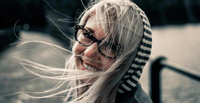 Das Gesicht einer lachenden Frau mit Brille, die sich umdreht, Stichwort Blue Monday. (c) Pixabay.com