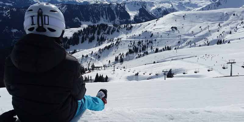 Ein Schifahrer sitzt oben auf einer Piste und schaut ins Tal. (c) Pixabay.com