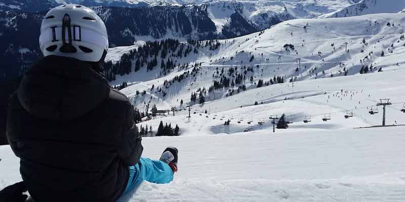 Stau- und stressfrei mit dem Zug in den Winterurlaub – so klappt`s 2 Ein Schifahrer sitzt oben auf einer Piste und schaut ins Tal. (c) Pixabay.com