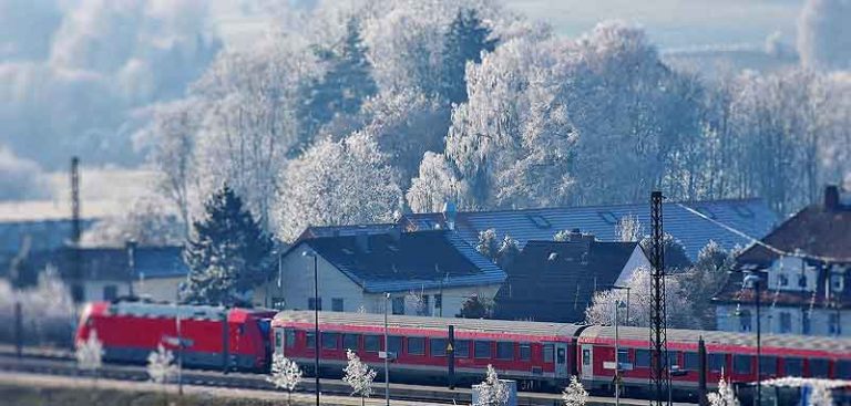 Ein Zug fährt durch eine Winterlandschaft mit weiß gefrorenen Bäumen. (c) Pixabay.com
