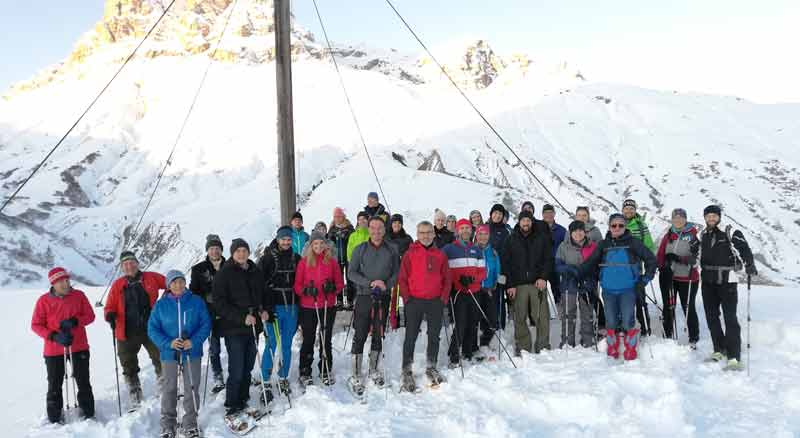 Eine Gruppe Schneeschuh-Wanderer vor einem Gipfelkreuz. (c) Wanderhotels.com