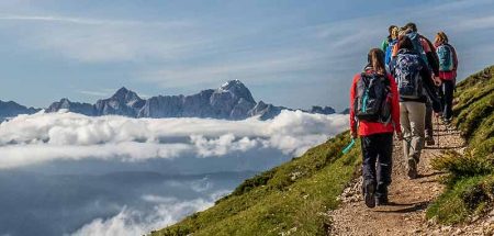 Eine Gruppe von Wanderern in den Bergen; über dem Tal liegt eine Wolkendecke. (c) Wanderhotels.com