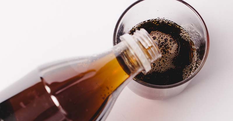 Cola, das von einer Flasche in ein Glas geleert wird. (c) Pixabay.com