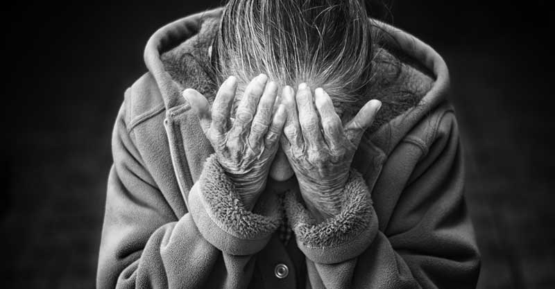 Eine alte Frau, die vor Trauer ihr Gesicht in ihren Händen vergräbt. (c) Pixabay.com