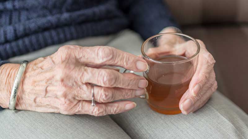 Harnwegsinfekt behandeln – es müssen nicht immer Antibiotika sein 2 Die Hände einer alten Frau, die ein Glas Tee hält. (c) Pixabay.com