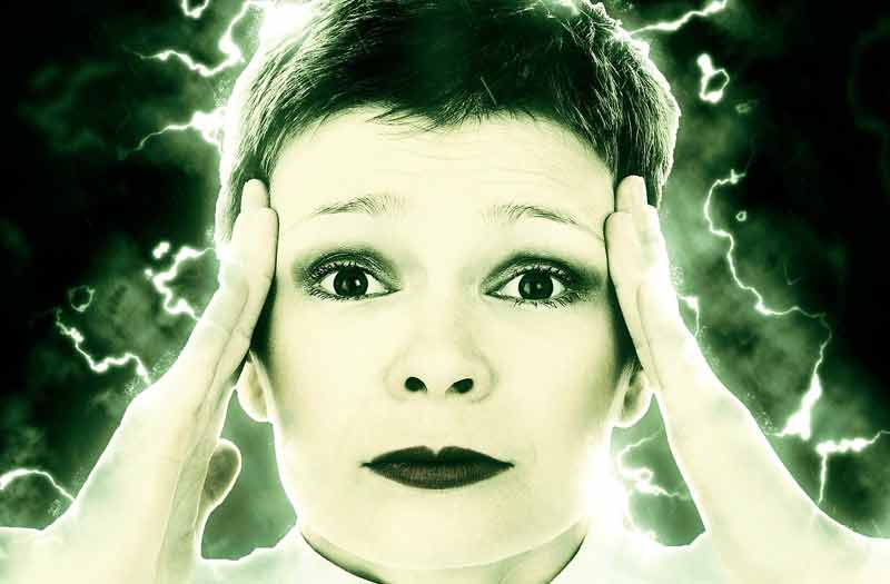 Der Kopf einer Frau, die sich mit beiden Händen auf die Schläfen greift; um sie herum Blitze als Zeichen für Migräne. (c) Pixabay.com