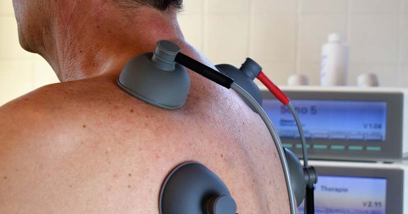 Der Rücken eines Mannes, der zur Stimulation der Muskeln mit Elektrotherapie behandelt wird. (c) Pixabay.com